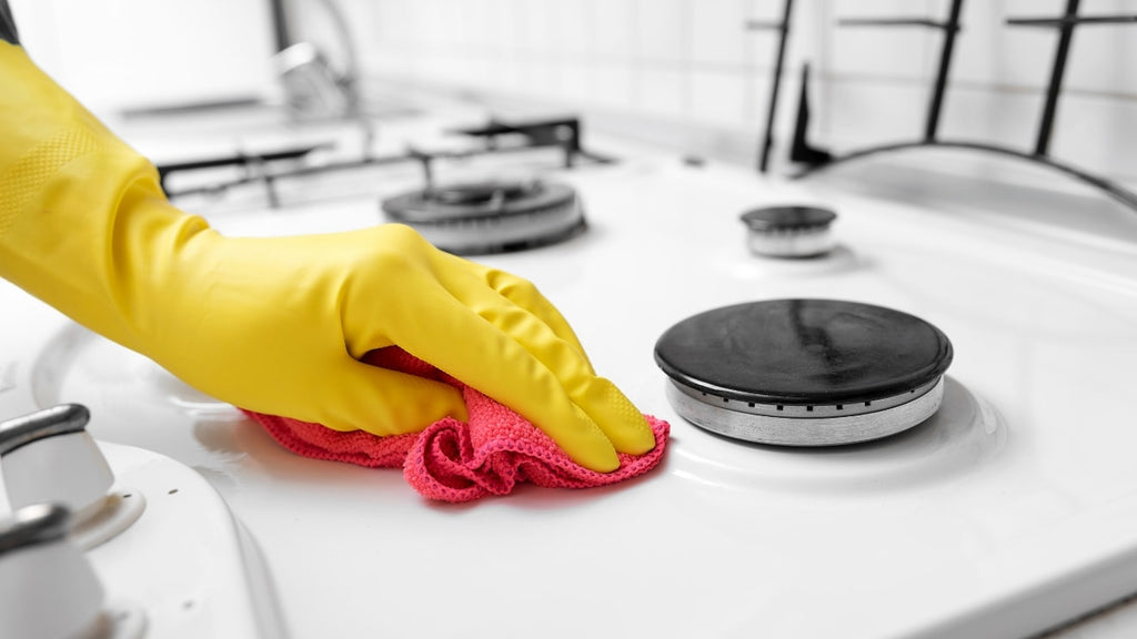 Gloved hand cleaning stove top